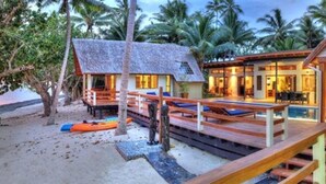 A beachfront property with a thatched-roof house, a wooden deck, and a pool area. - Beachfront Private Villa (Korolevu)