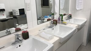 Un baño moderno con dos lavamanos, un espejo grande y diversos artículos de aseo.