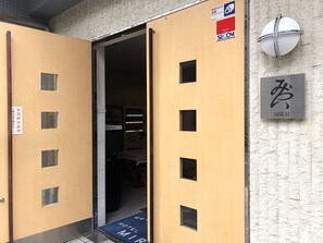 A hotel entrance with a wooden door, a security camera, and a sign indicating security by SECOM. - Hotel Mirai (Yokohama)