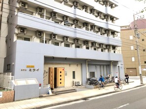 A multi-story hotel with a tiled facade, a visible entrance, and bicycles parked outside. - Hotel Mirai (Yokohama)