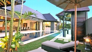 A modern house with a swimming pool, outdoor seating, and a covered patio area. - Modern Family Villa (Kerobokan)
