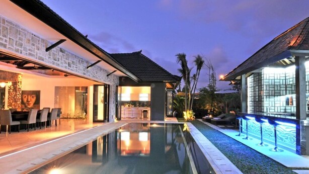 A modern pool area with a clear pool, adjacent lounge seating, and a well-lit outdoor space. - Modern Family Villa (Kerobokan)