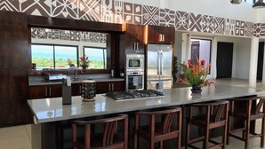 A modern kitchen with a large island, stainless steel appliances, and a view of the ocean. - Fiji Luxury Pool Villa (Lautoka)