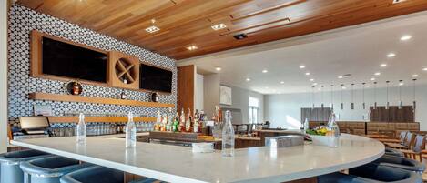 A modern kitchen with a central island, bar stools, and a variety of kitchen appliances.