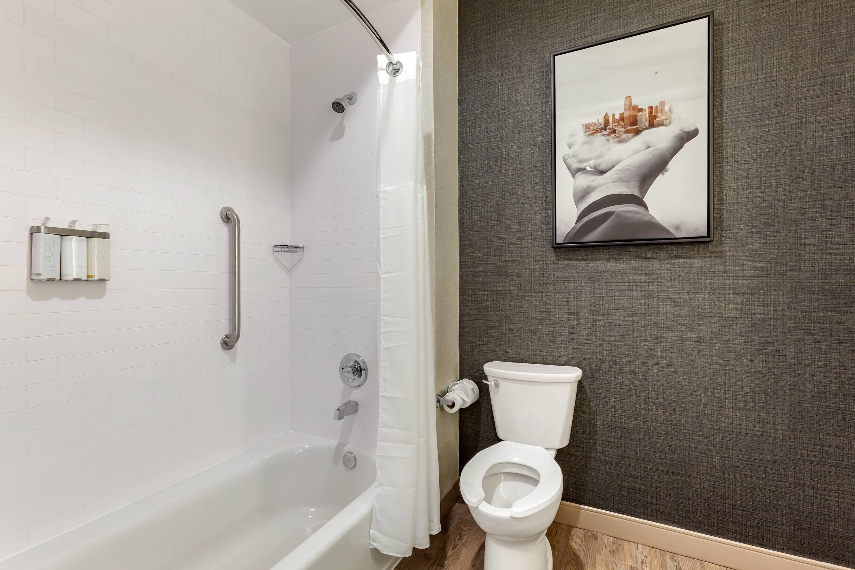 Une salle de bain avec une baignoire blanche, des toilettes et un rideau de douche.