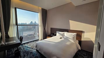 Una habitación de hotel con un ventanal grande, una cama, un escritorio y una silla.