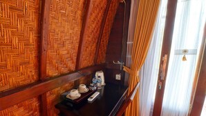 A room with a wooden wall, a black table with a coffee maker, cups, and a remote control. - Butterfly Bungalows (Penida Island)