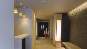 Ein moderner Flur mit Fliesenboden, Pendelleuchten, einer Rezeption und einer Wand mit Ziegeloptik.