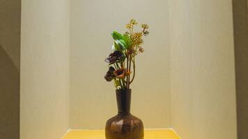 Un vase rempli de fleurs est posé sur une table jaune, devant un mur de couleur beige.