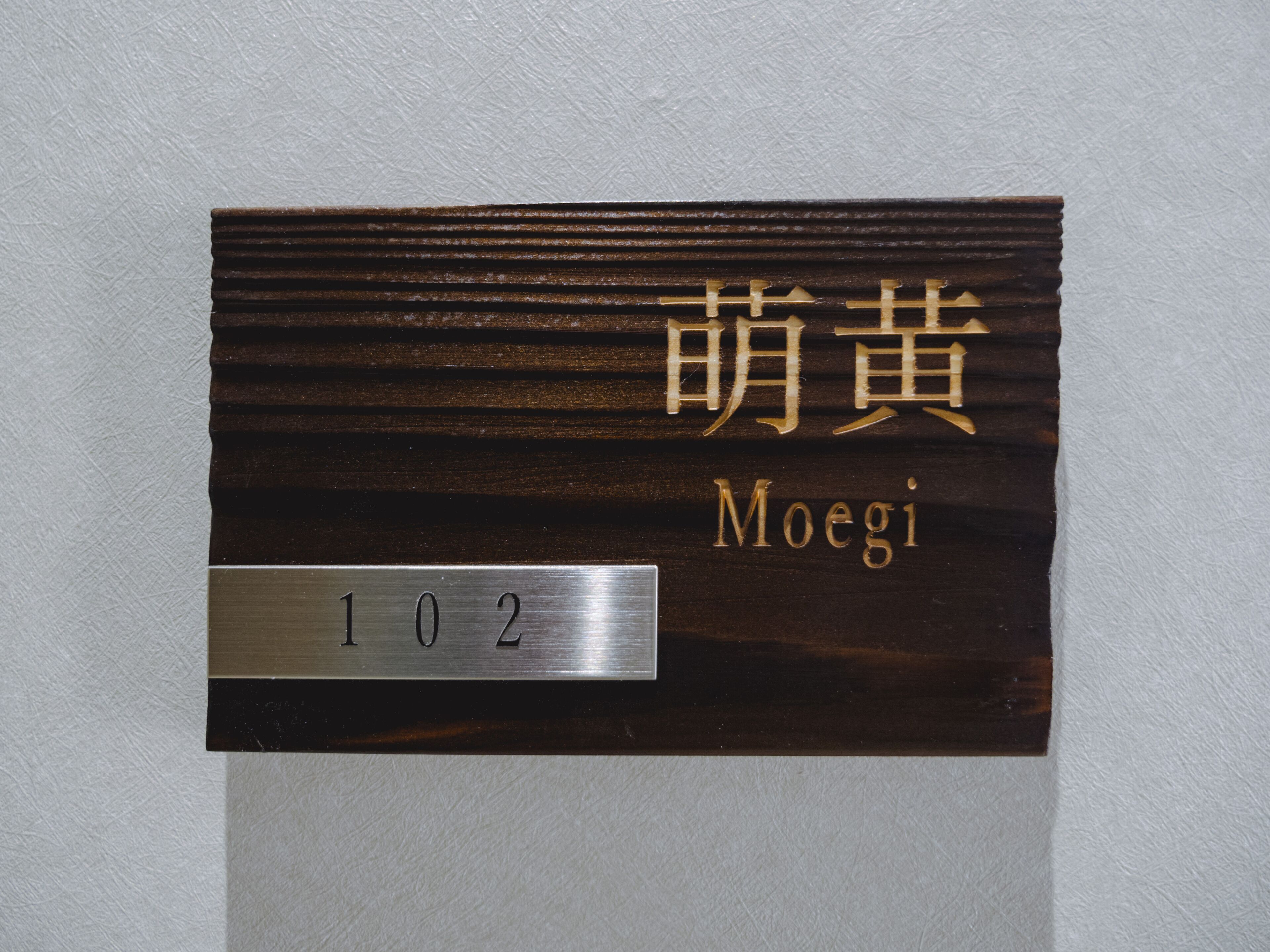 A room number plaque with the number 102 and the name "Moegi" in both English and another script.