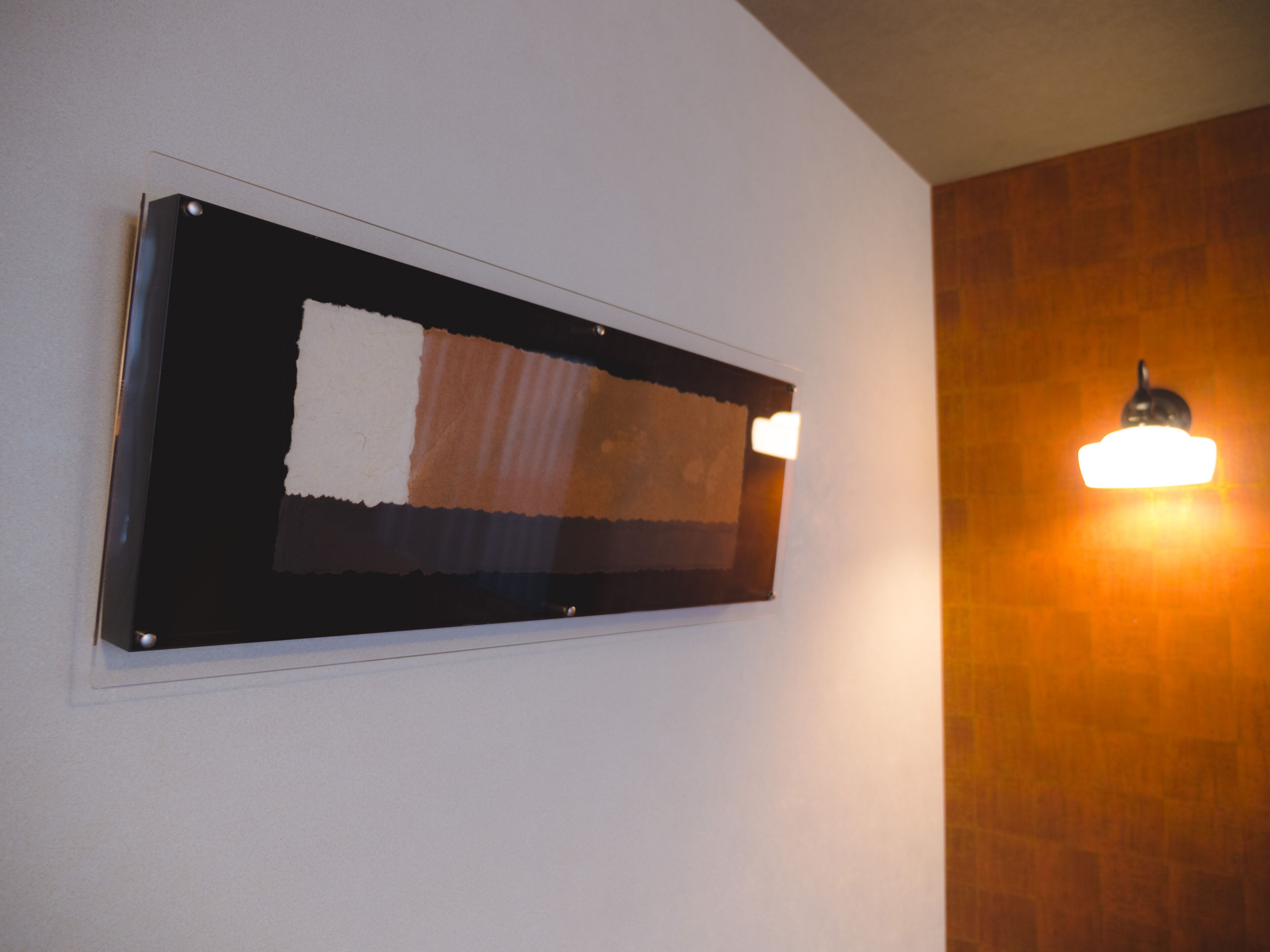A wall-mounted light fixture and a framed artwork with a torn section.
