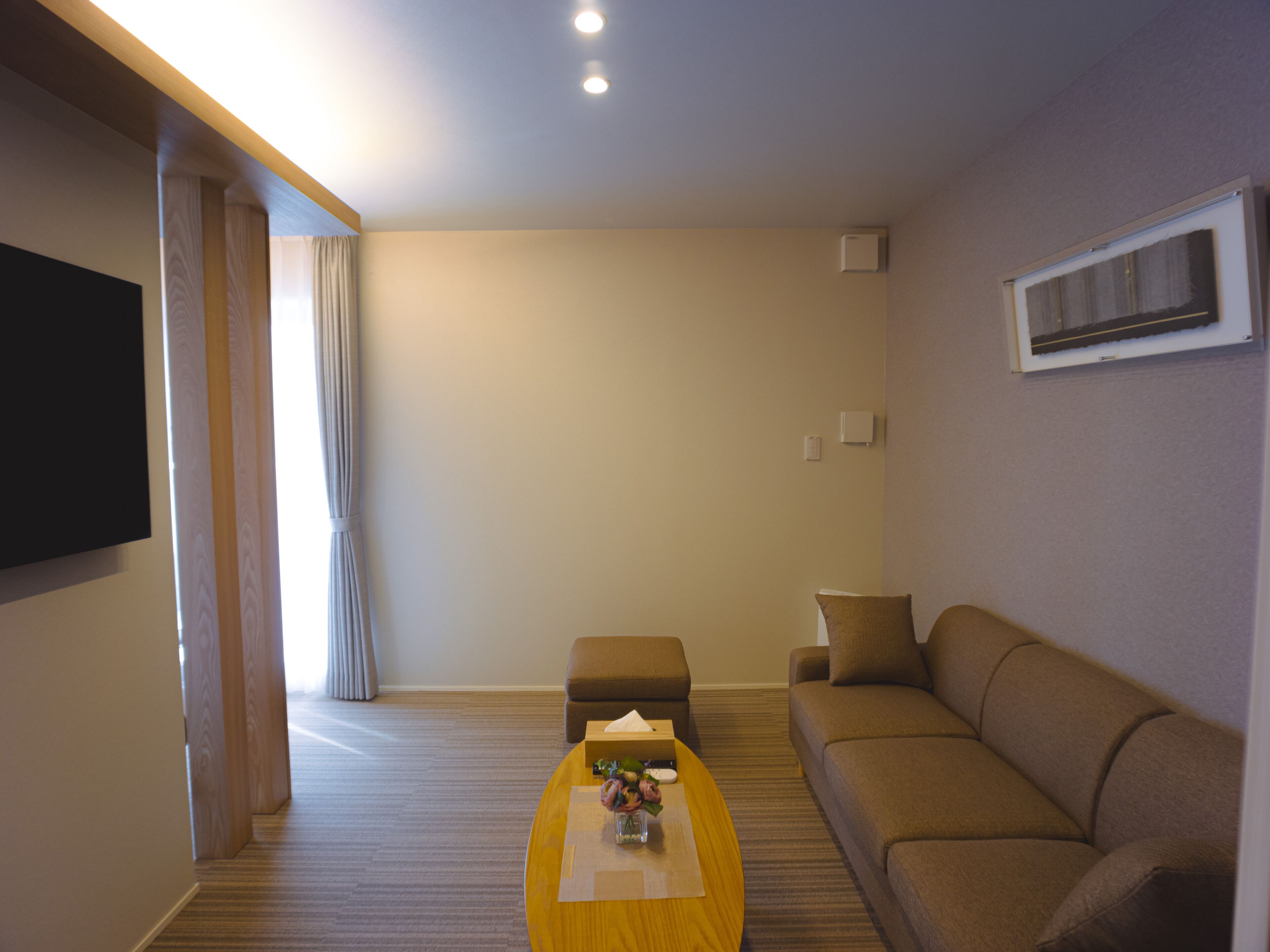 Una sala de estar moderna con un sofá, una mesita de centro y un televisor de pantalla plana montado en la pared.