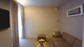 Una sala de estar moderna con un sofá, una mesita de centro y un televisor de pantalla plana montado en la pared.