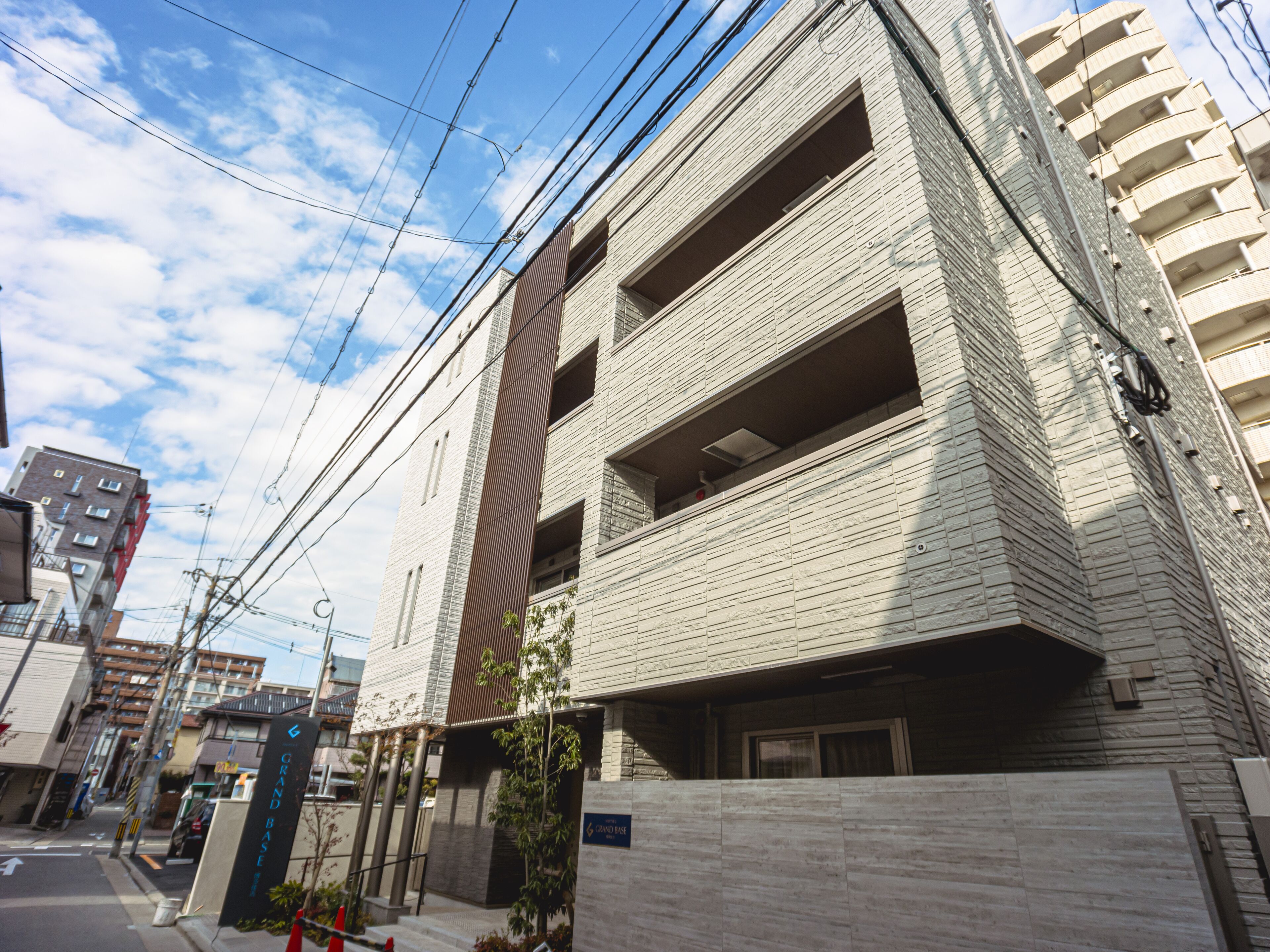 A modern building with a brick facade, multiple balconies, and a visible entrance with a sign.