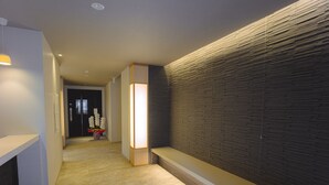 Ein moderner Flur mit Fliesenboden, einer Bank und einer Wand mit Strukturmuster.