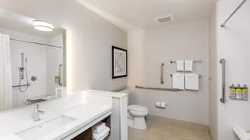 Un baño moderno con un espejo grande, dos lavamanos, un inodoro y una zona de ducha.
