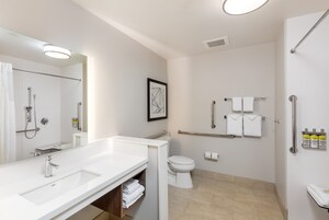 Un baño moderno con un espejo grande, dos lavamanos, un inodoro y una zona de ducha.