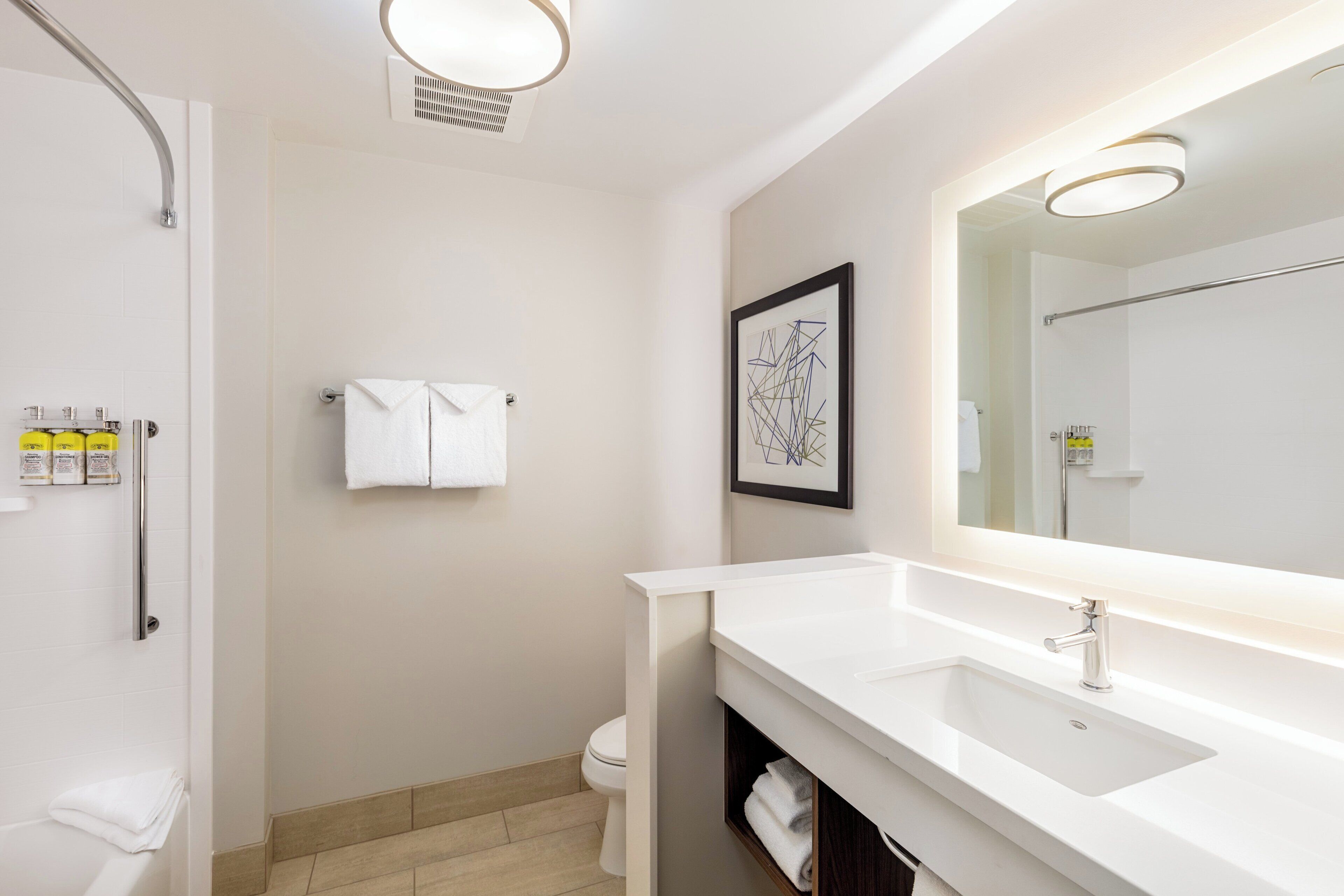 A modern bathroom with a white sink, a large mirror, and a shower.