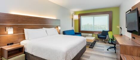 Moderni hotellihuone, jossa on suuri sänky, työpöytä, tuoli ja televisio.