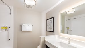A modern bathroom with a white sink, a large mirror, and a shower.