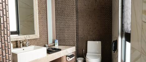 A bathroom with a sink, mirror, toilet, and shower.