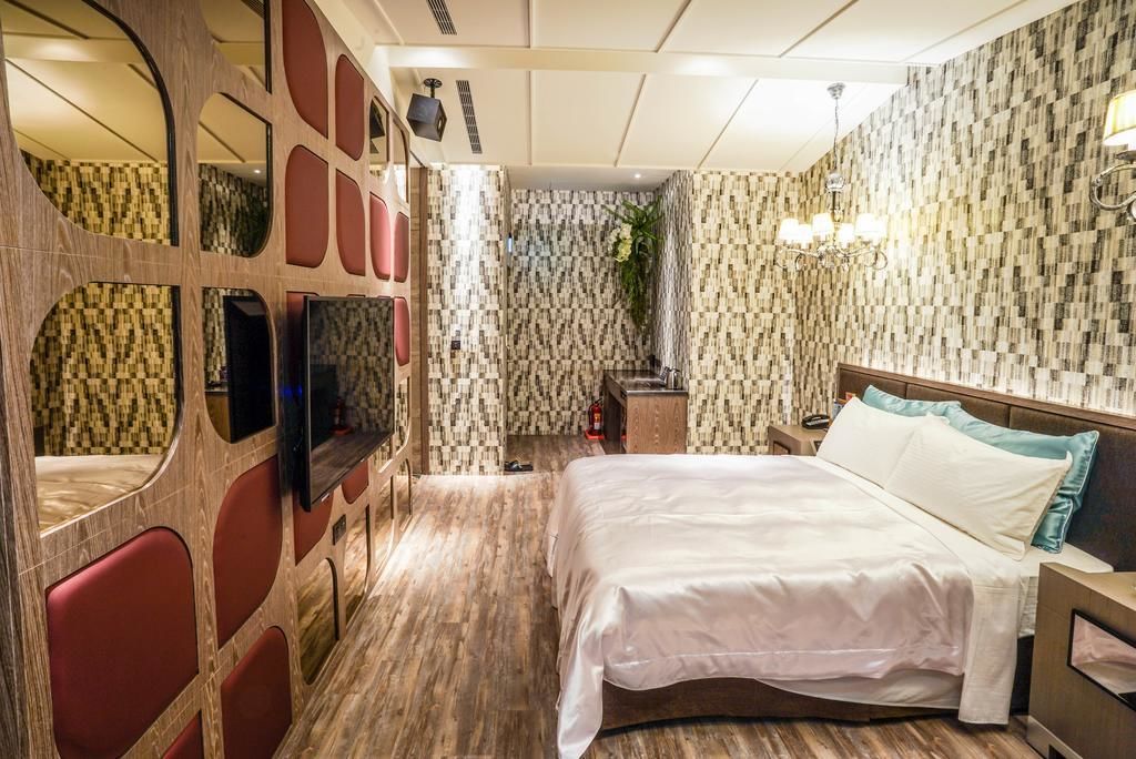 Une chambre d’hôtel équipée d’un lit, d’une télévision, d’un miroir et d’un espace douche.
