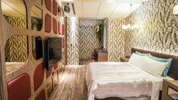 Une chambre d’hôtel équipée d’un lit, d’une télévision, d’un miroir et d’un espace douche.
