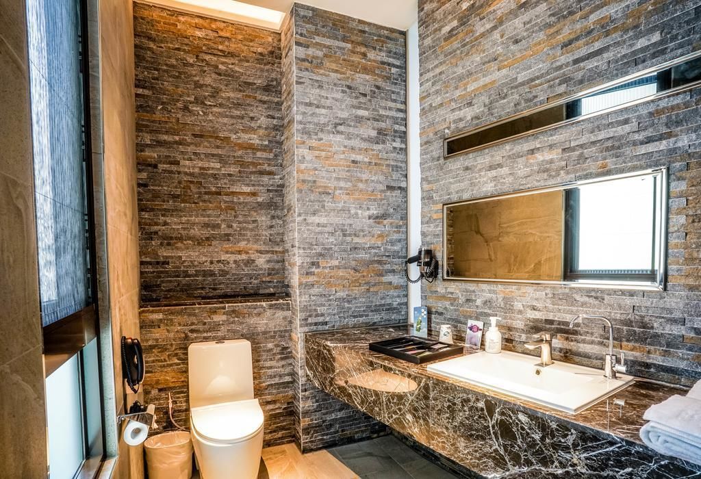 A modern bathroom with a stone wall, a marble sink, and a large mirror.
