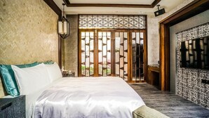 A bedroom with a large bed, a TV, and a decorative screen door. - Shu Lan Motel (Nantou)