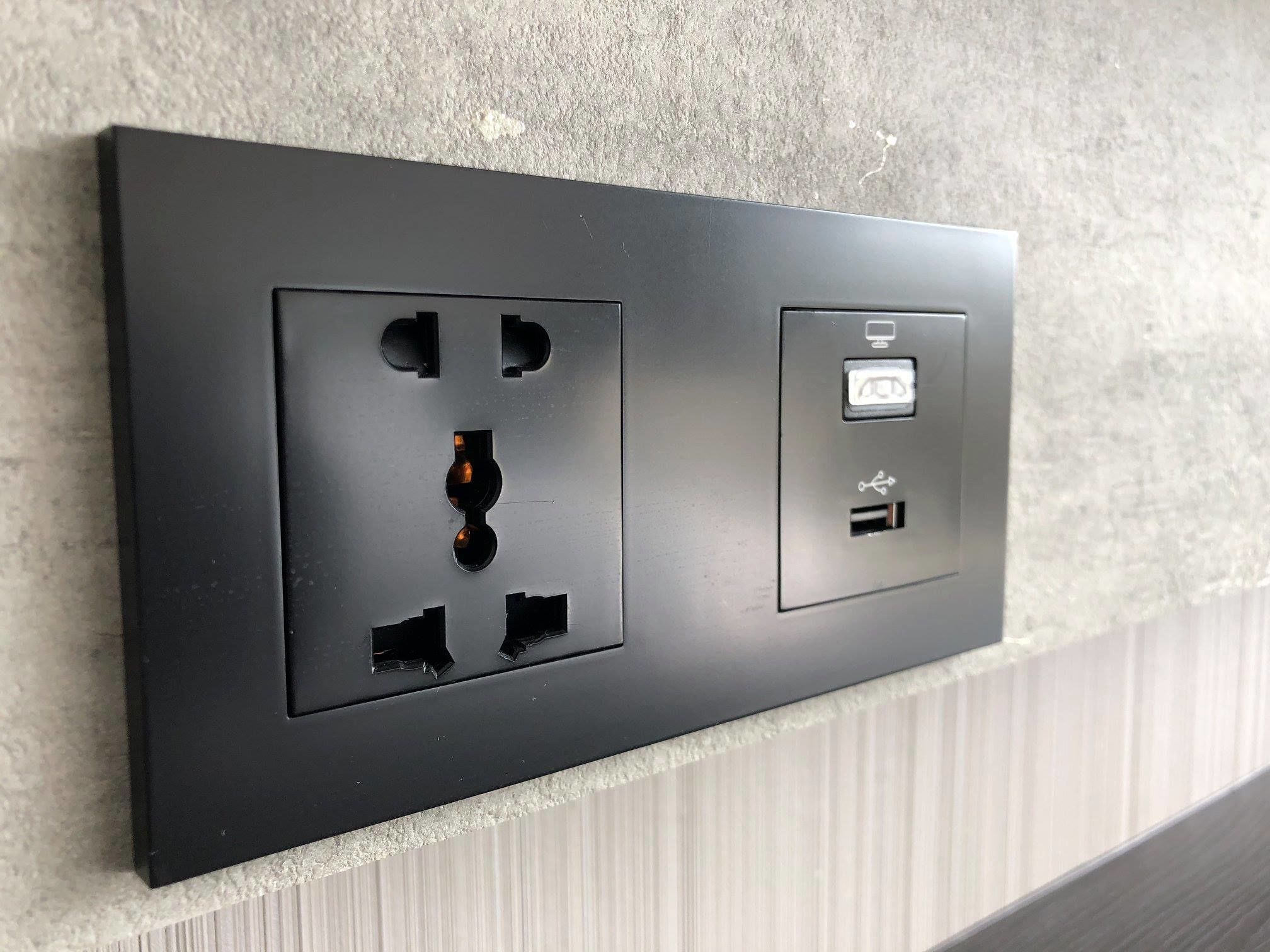 Presta d'electricitat negra amb port USB i presa de corrent a una paret amb relleu.