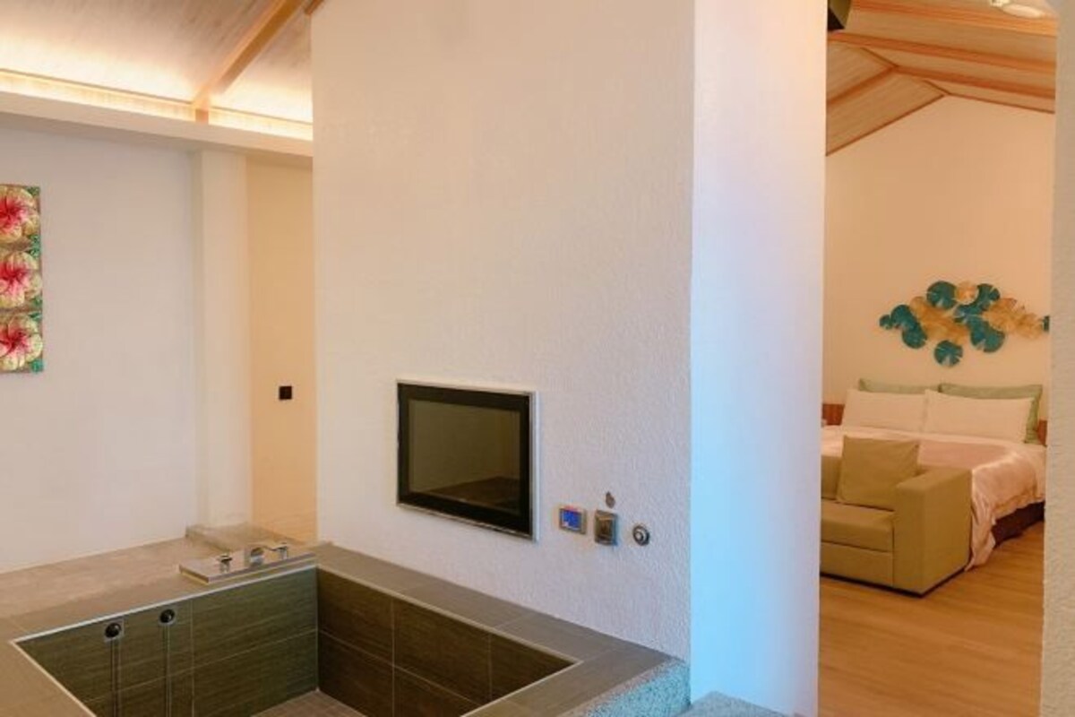 A modern bathroom with a built-in shower, a mounted TV, and a small sink.