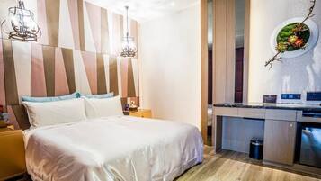 Een moderne hotelkamer met een groot bed, een houten hoofdbord, een ingebouwde bureau met een magnetron en een kleine prullenbak.