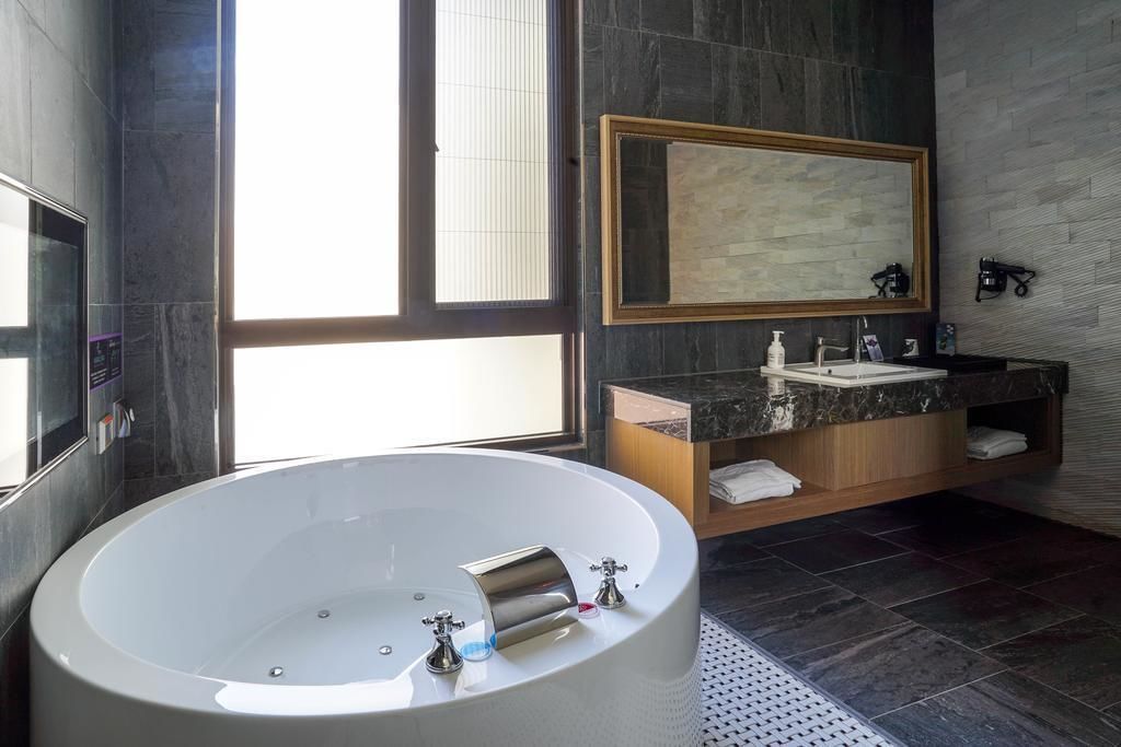 A modern bathroom with a freestanding bathtub, a large mirror, and a vanity with a marble countertop.