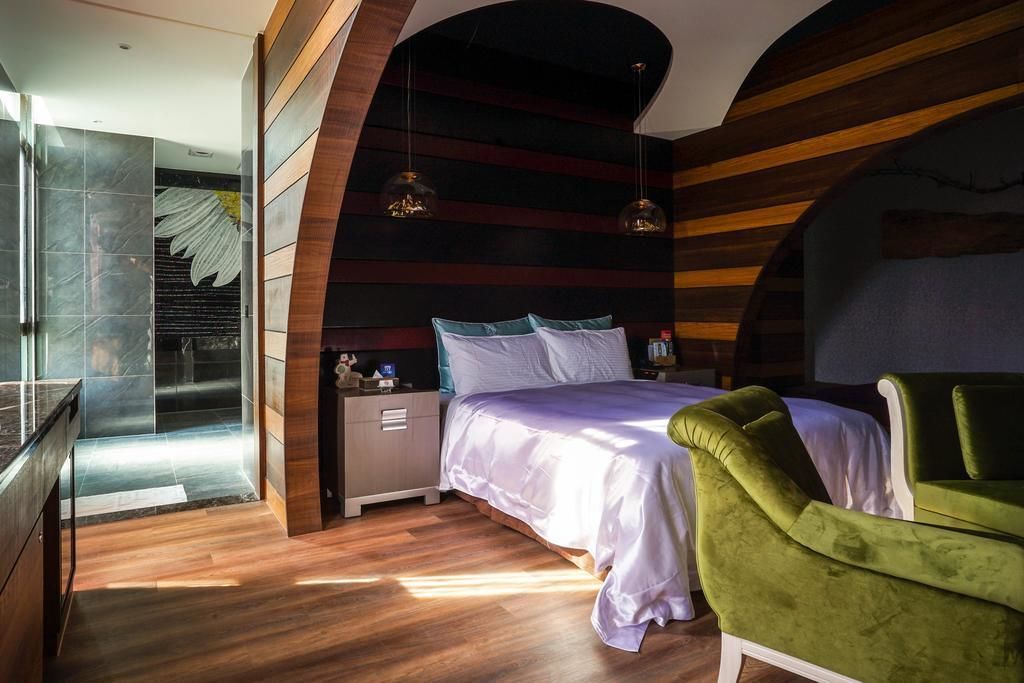 A modern bedroom with a bed, nightstands, and a green armchair.