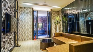 A modern lobby with a seating area, a glass partition, and a plant. - Shu Lan Motel (Nantou)