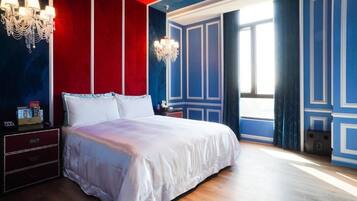 Ein Schlafzimmer mit einem großen Bett, zwei Nachttischen, einer Chandelüster und einem fenster mit Vorhängen.