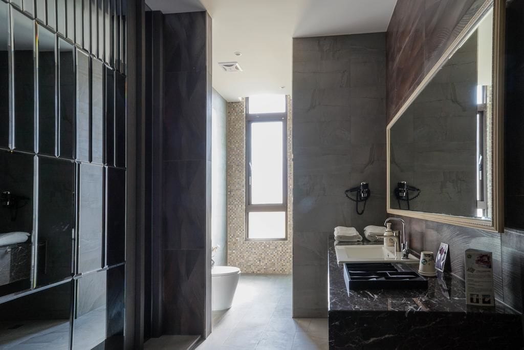 Een moderne badkamer met een grote spiegel, een bad en een toilet.