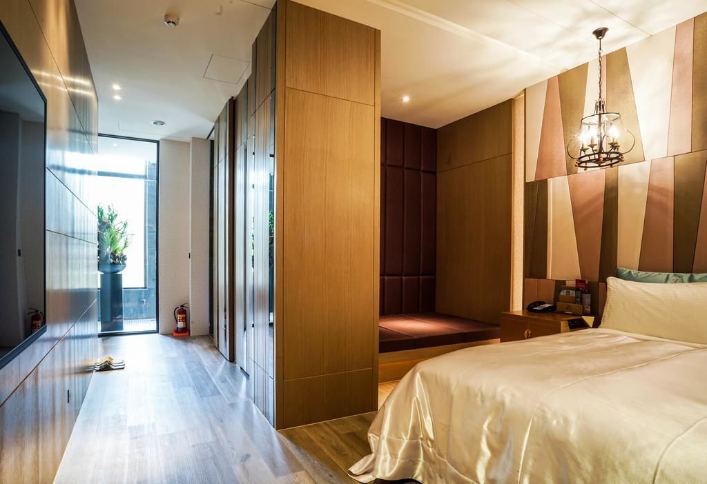 A modern hotel room with a large bed, a seating area, and a view of the outdoors.