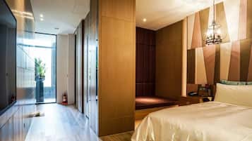 A modern hotel room with a large bed, a seating area, and a view of the outdoors.
