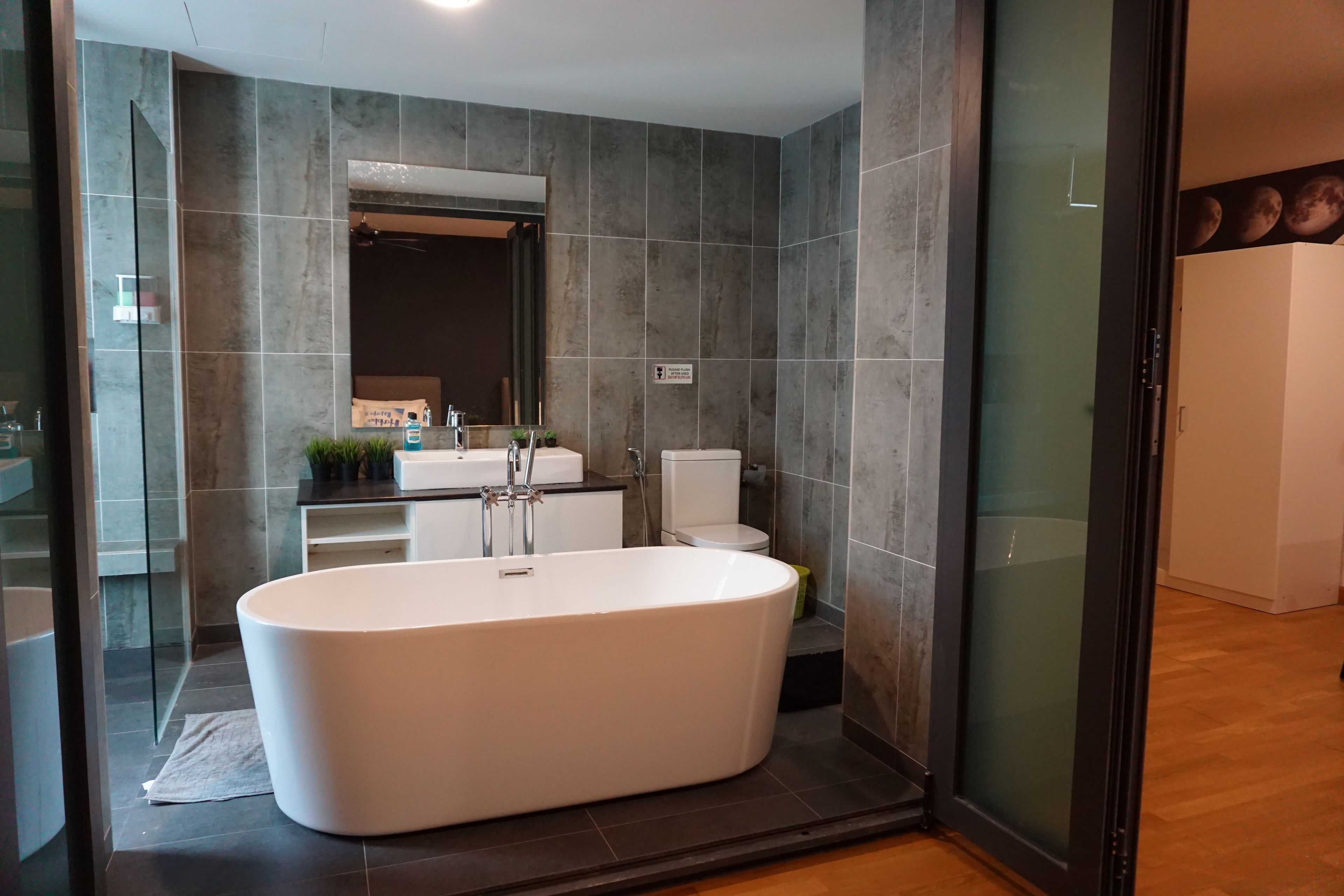 A modern bathroom with a freestanding bathtub, a large mirror, and a toilet.