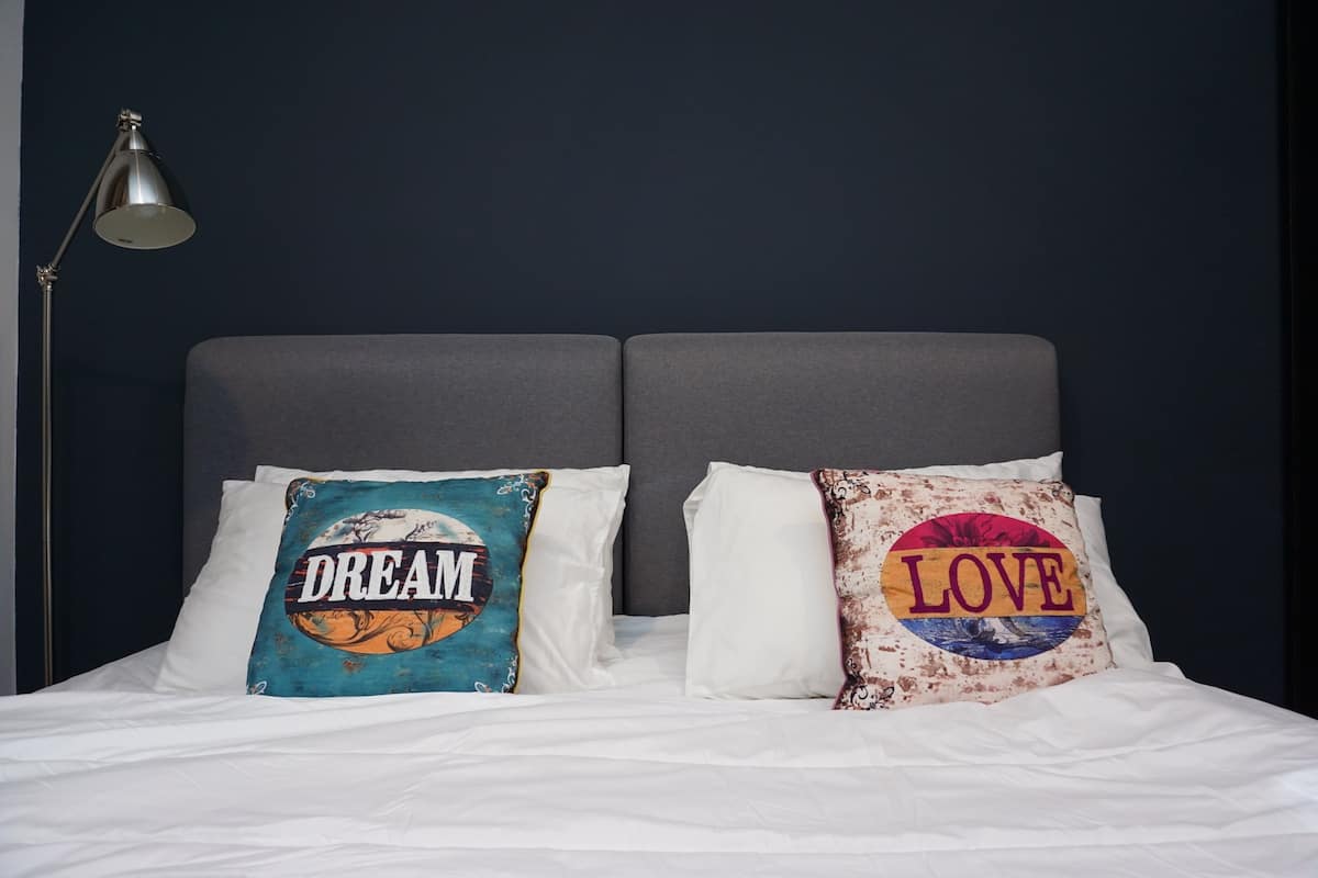 A bed with two pillows, one with 'DREAM' and the other with 'LOVE' printed on them.