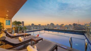 Una piscina al aire libre, sombrillas, sillones reclinables de piscina