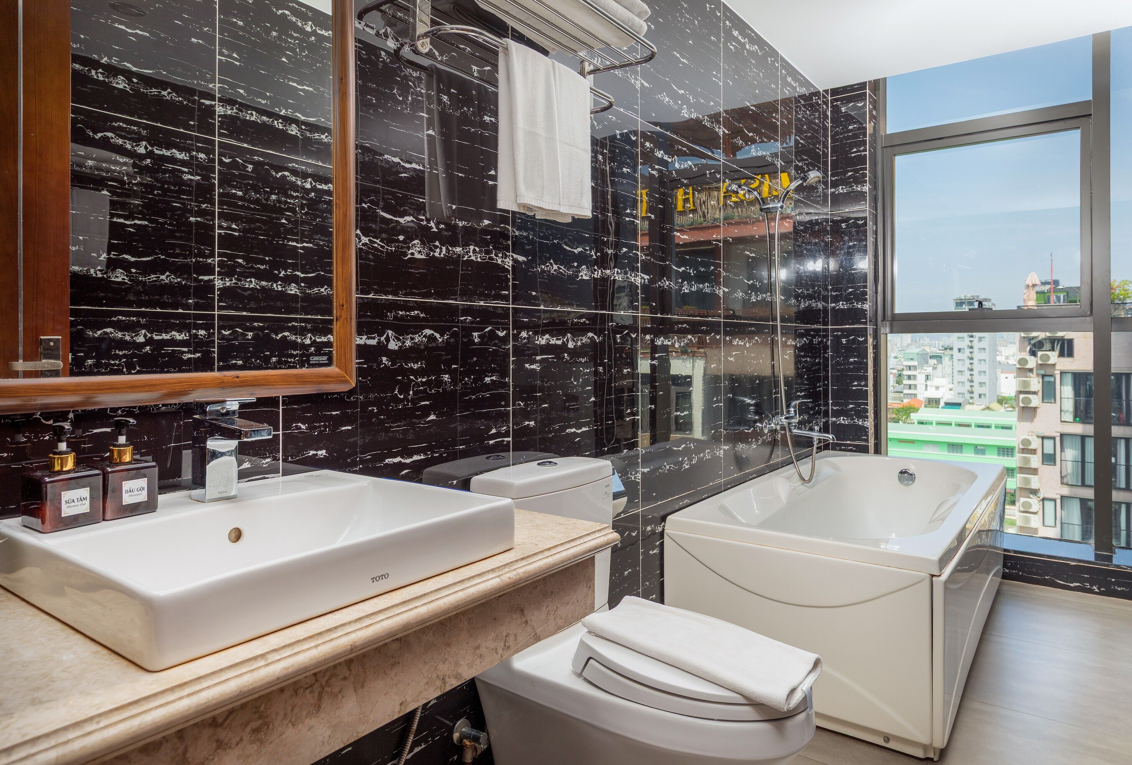 Une salle de bain moderne avec un grand miroir, deux lavabos, une baignoire et des toilettes.