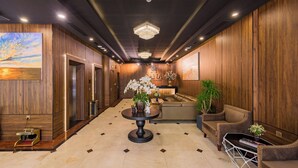 A lobby with a round table, sofas, and a chandelier. - Sana Danang Beach Hotel (Da Nang)