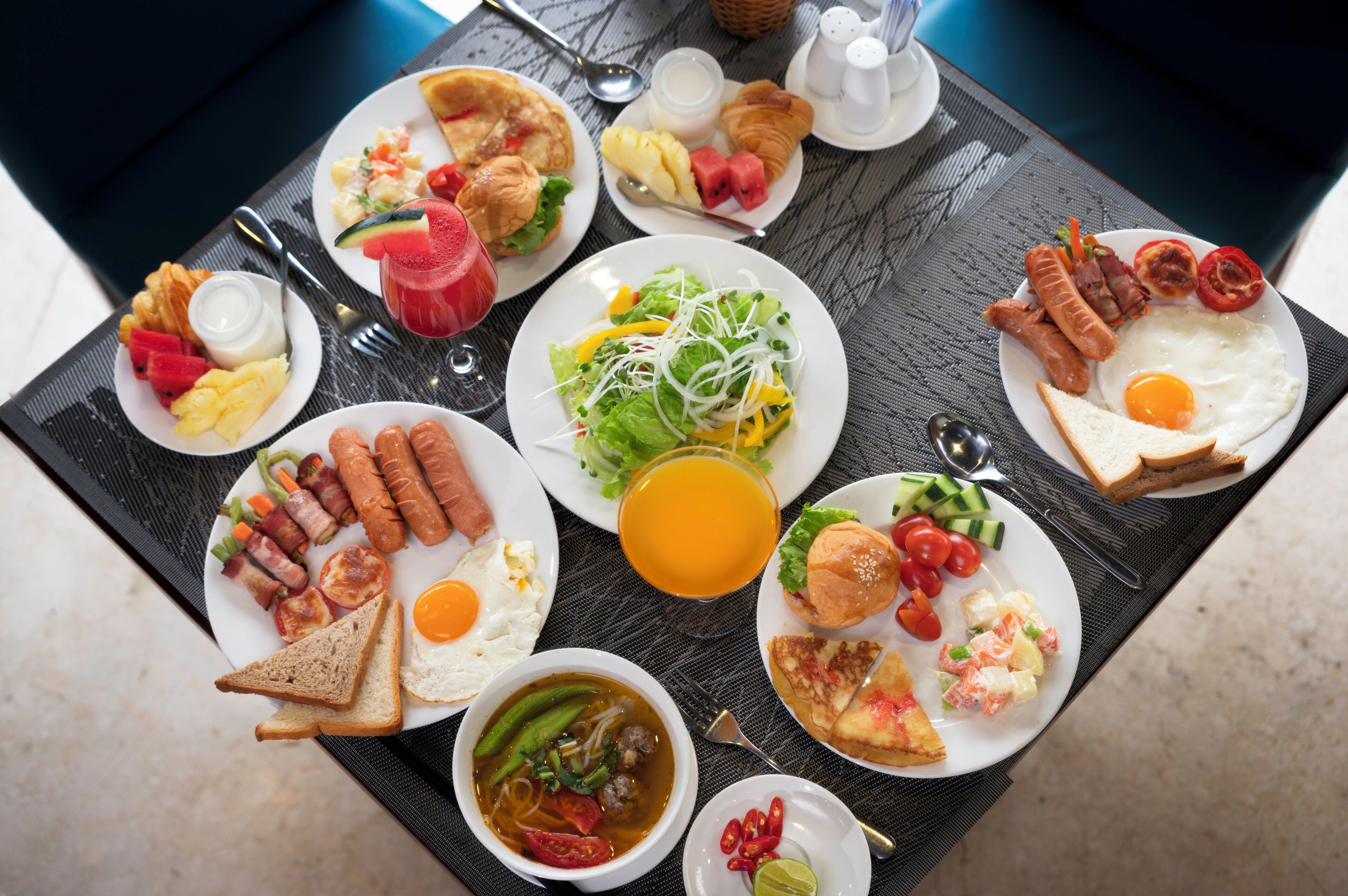 A table with a variety of breakfast dishes including eggs, sausages, toast, and a salad.
