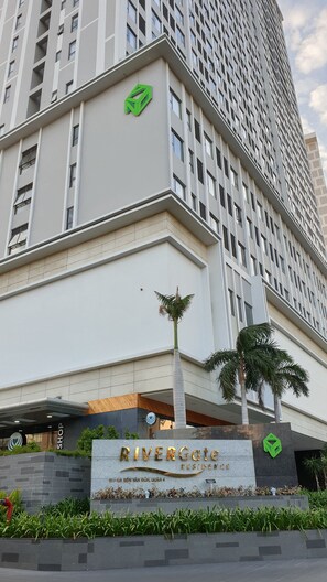 A modern building with a sign reading "RIVERGate RESIDENCE" and a logo above it. - Stay In Vietnam River Gate (Ho Chi Minh City)