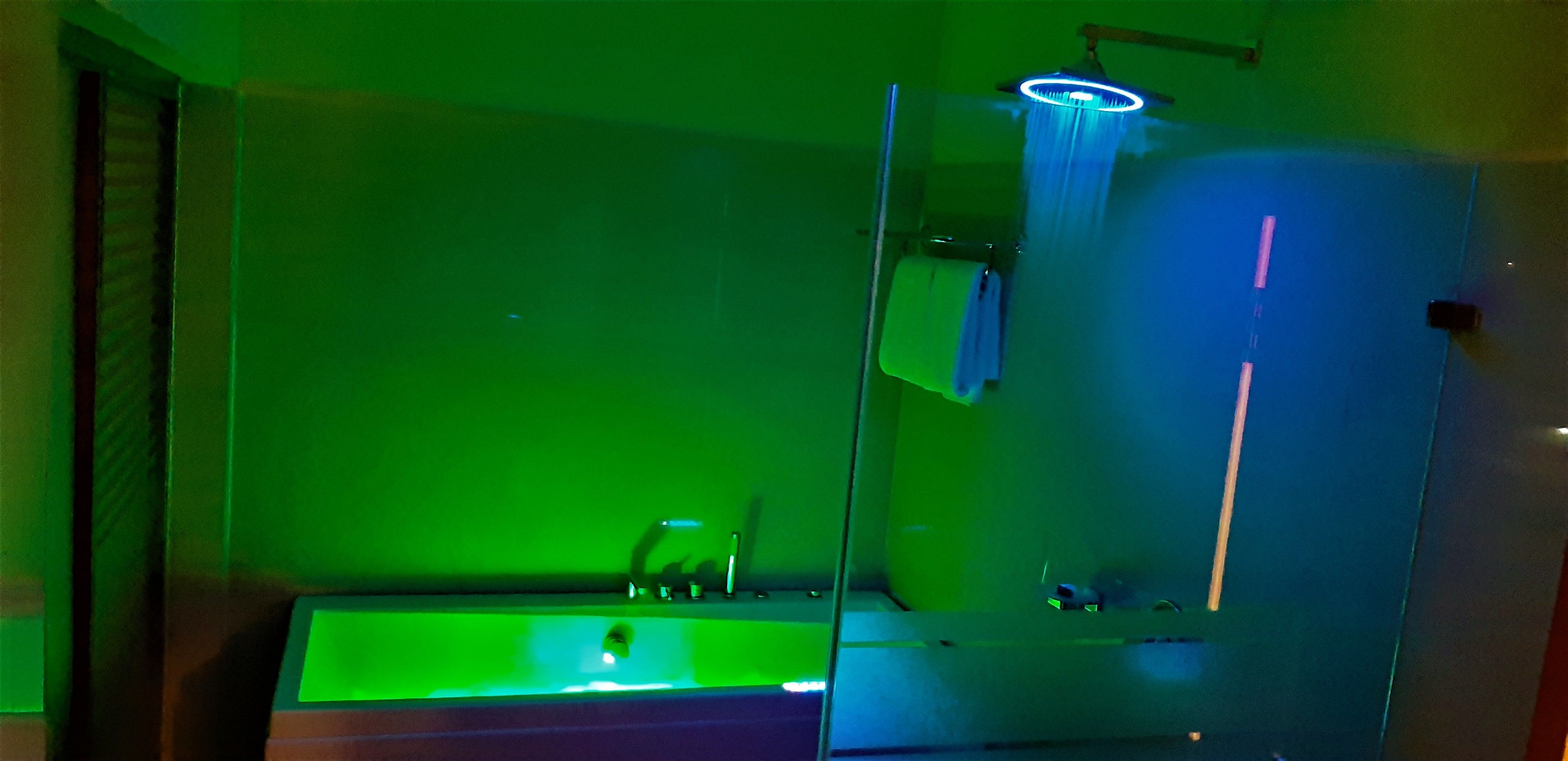 A bathroom with a green-lit sink and a mirror.