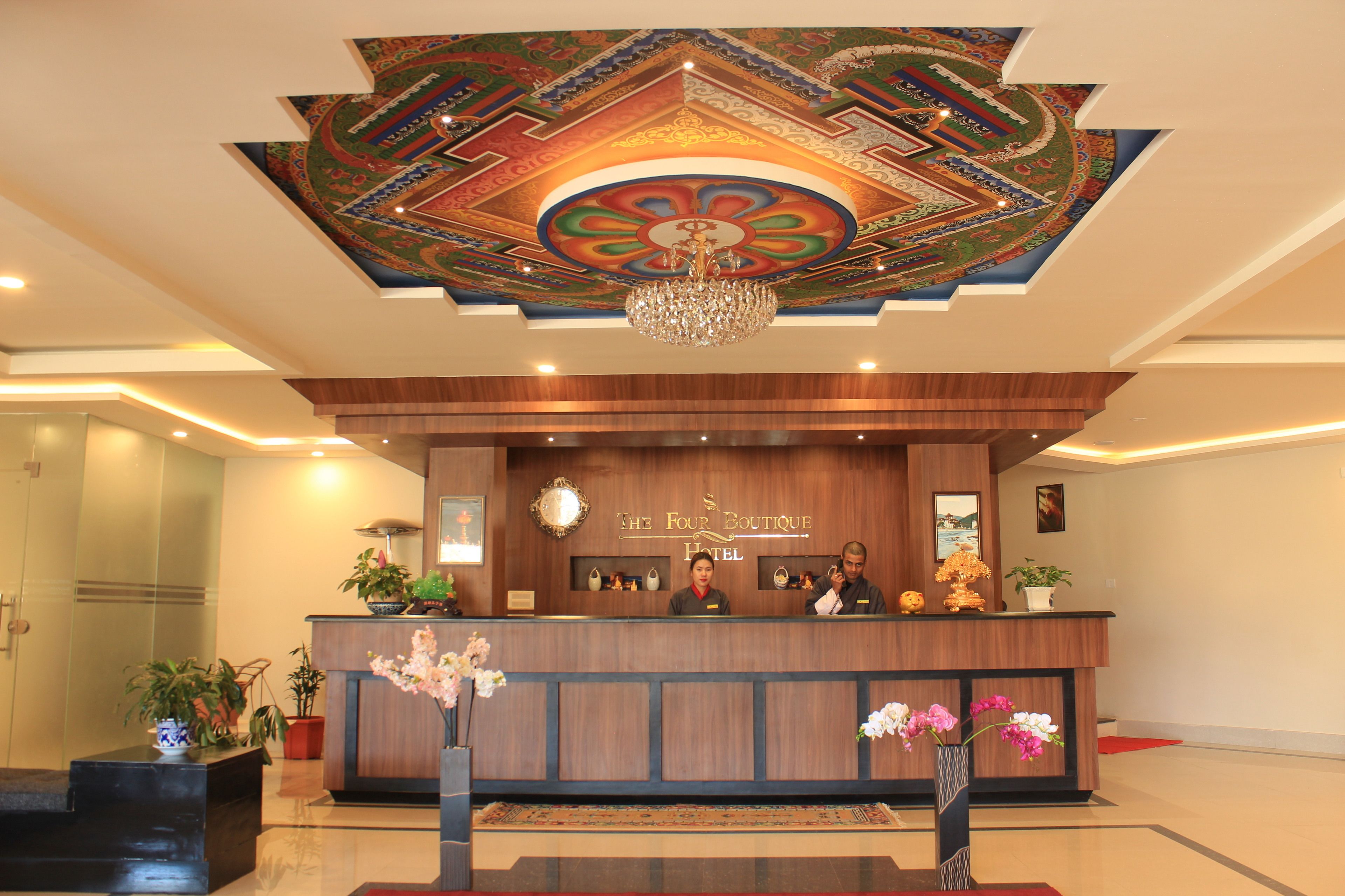 Una recepción de hotel con techo decorativo, una araña y un letrero que dice "The Four Boutique Hotel".
