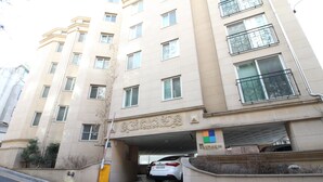 Um edifício de vários andares com entrada de garagem, um carro branco estacionado no interior e uma placa com caracteres chineses.
