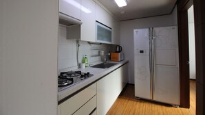 Uma cozinha compacta com armários brancos, uma pia de aço inoxidável, micro-ondas e geladeira.